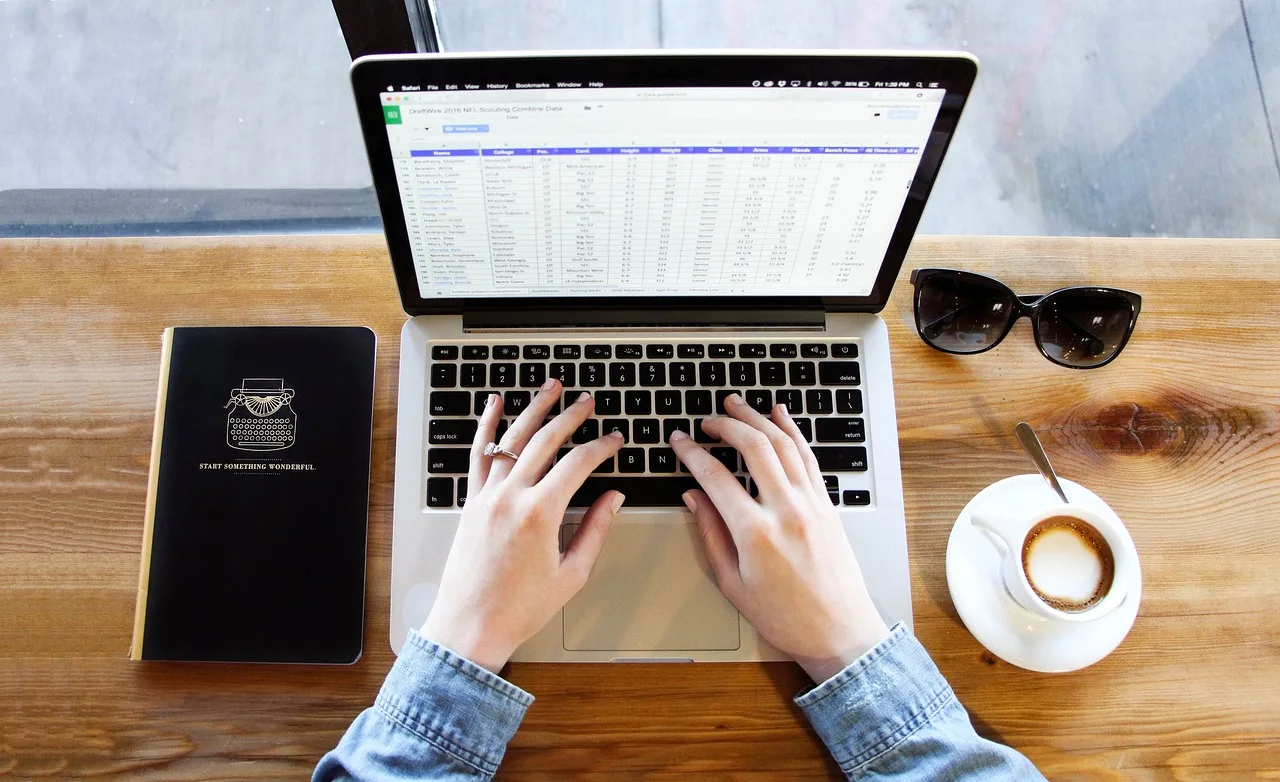 Hands typing on a laptop next to a cup of coffee, moving bookmarks and passwords before the Arc browser shutdown
