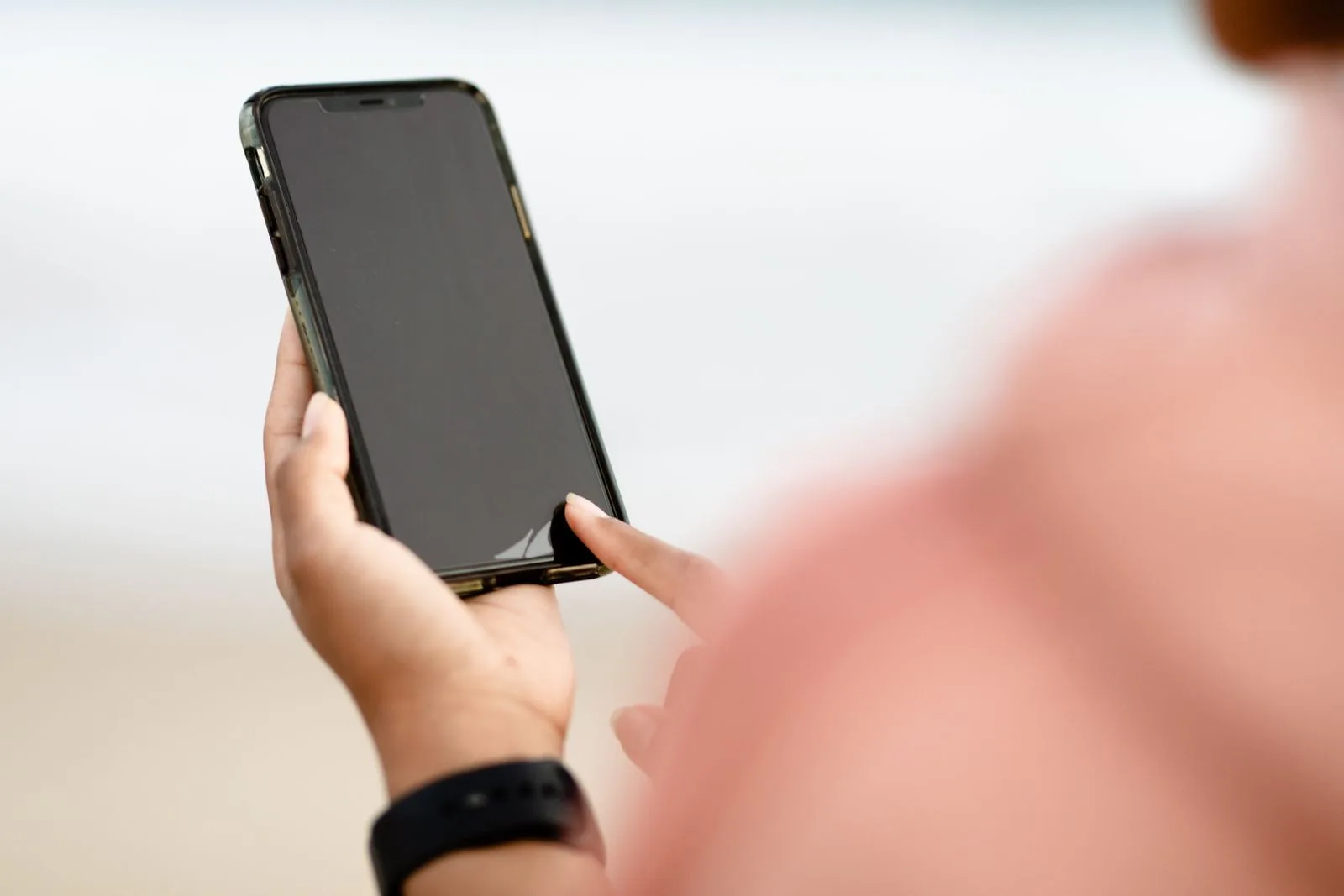 Hand tapping a smartphone screen outdoors, changing iPhone settings after the iOS 27.2 update