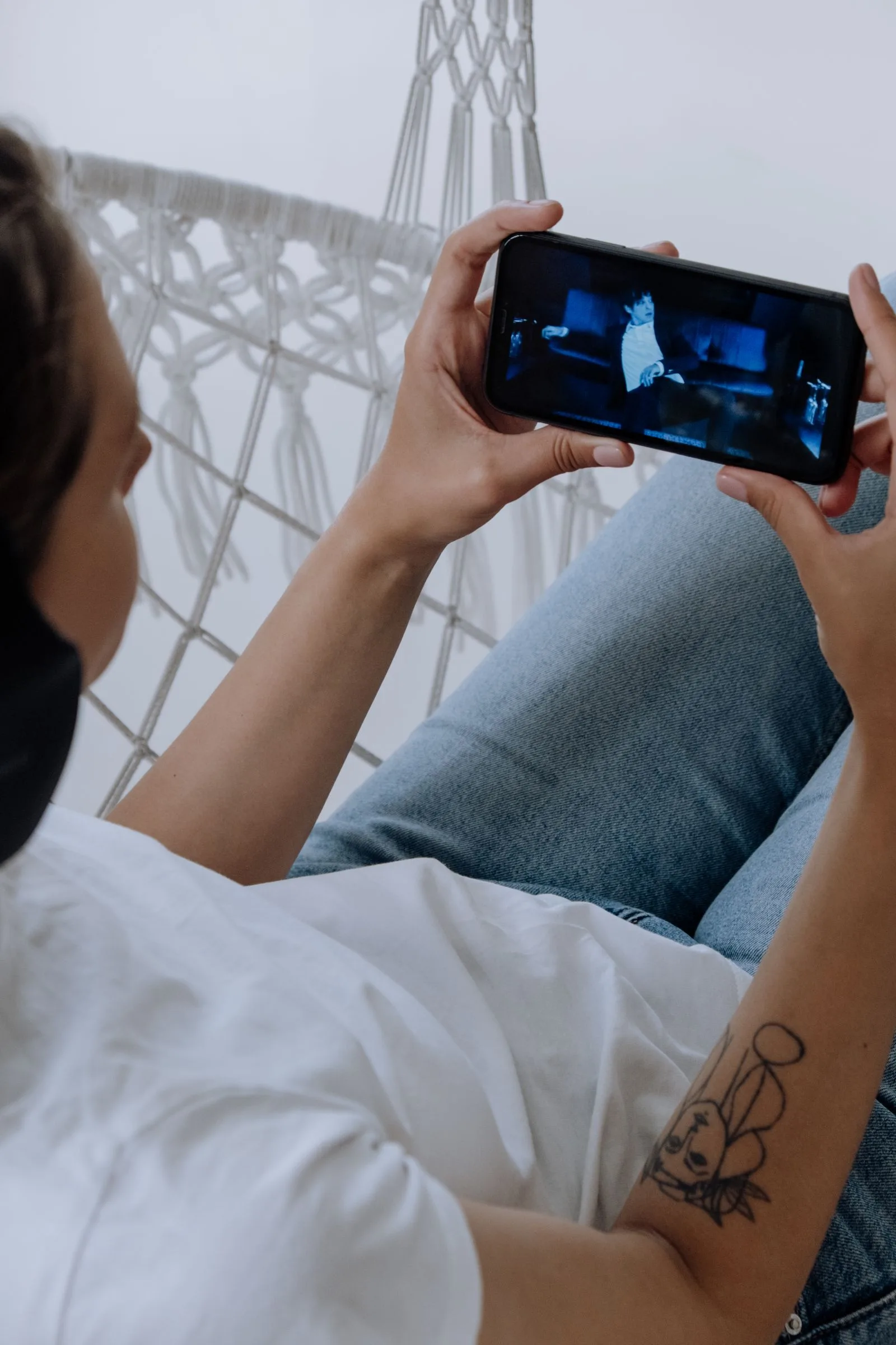 Woman wearing headphones watching a video on her smartphone, using a custom YouTube feed