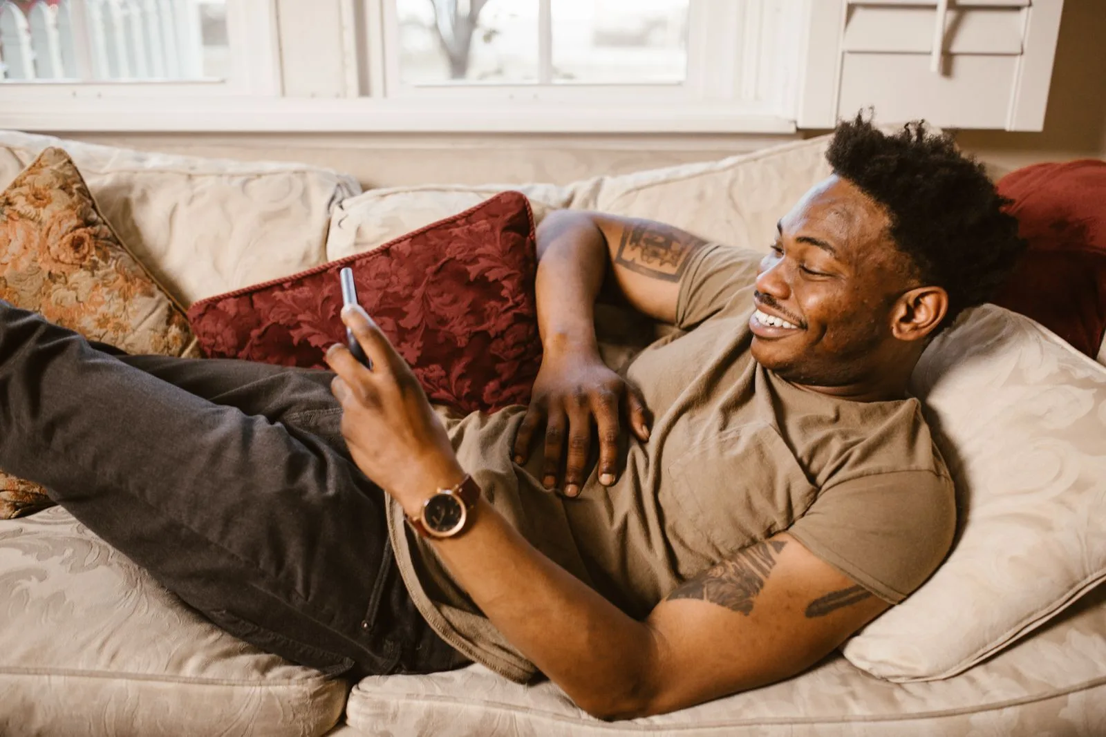 Man lying on a couch scrolling videos on his smartphone, finding the new YouTube Subs tab